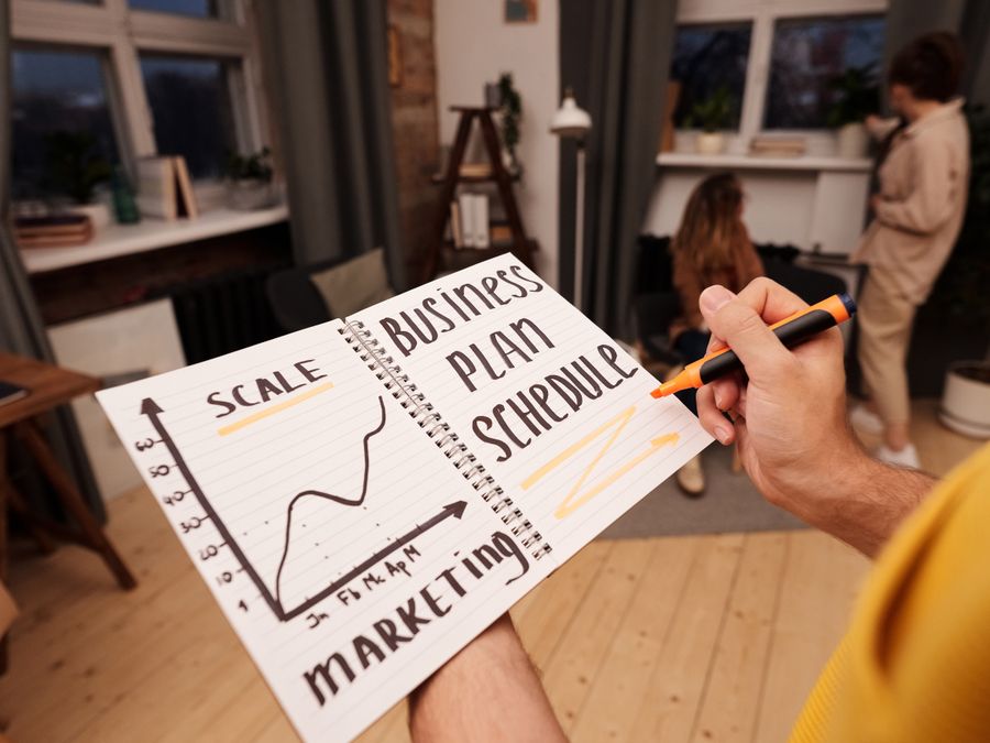Person holding a notebook with planning details and graph for business strategy indoors.