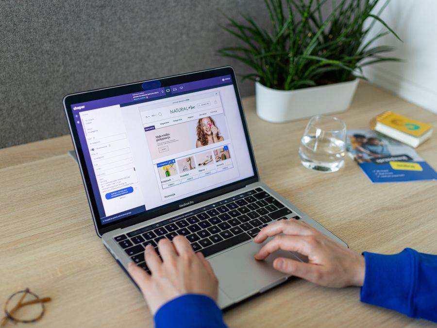 A person navigating an online store on a laptop, at a modern indoor office desk.