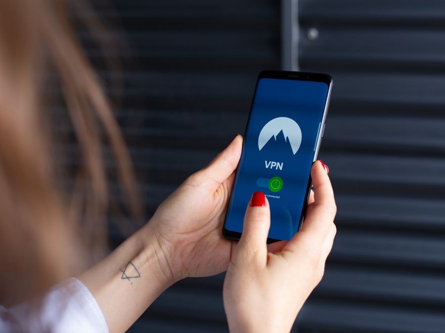 Close-up of a woman's hands using a VPN app on a smartphone, emphasizing digital security.