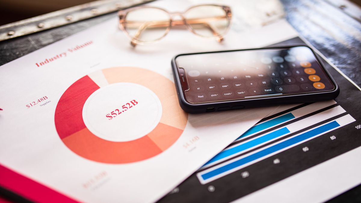 Smartphone on business documents with charts and graphs, illustrating financial analysis.