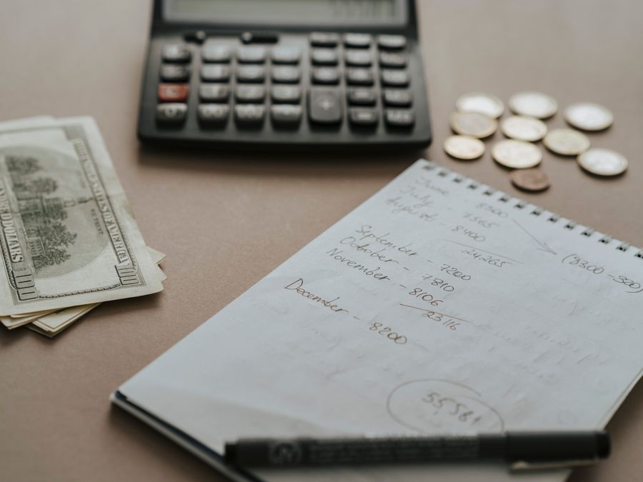 Desk setup showing calculator, cash, coins, and financial notes for budgeting.