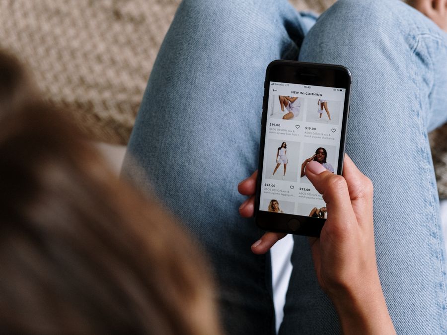 A woman uses her smartphone to shop for clothing online, showcasing digital retail technology.