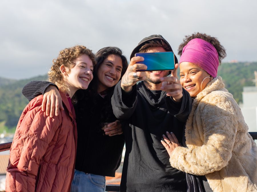 A joyful group of friends taking a selfie on a sunny rooftop in Portugal, showcasing togetherness and happiness.
