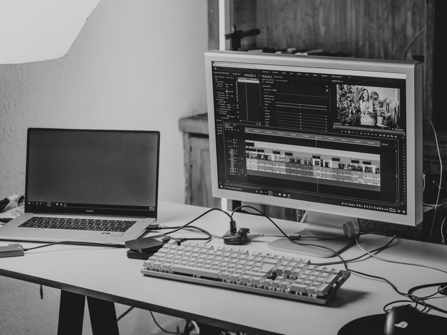 A monochrome workspace setup featuring a laptop and monitor for video editing.