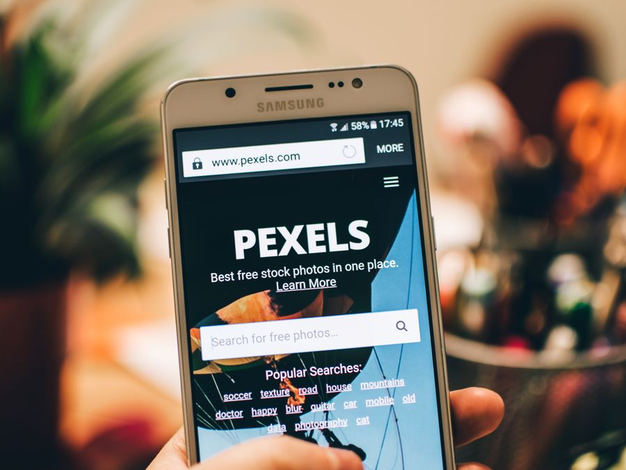 A close-up view of a smartphone displaying the Pexels website screen for stock photo searches.