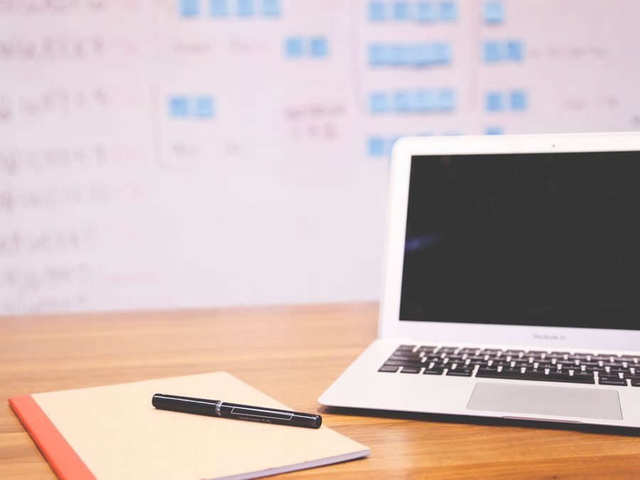 Clean and organized workspace with a laptop, notepad, and pen for planning and projects.