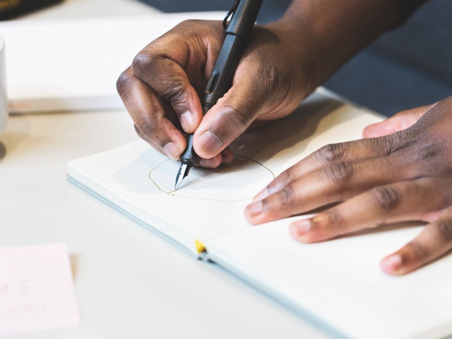 Close-up of a man writing with a fountain pen in a notebook, indoors.