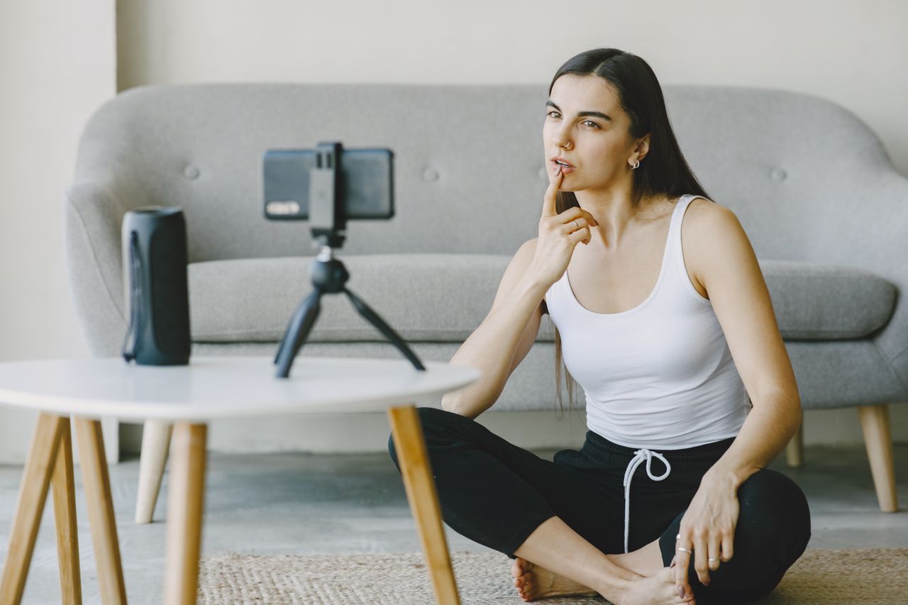 Nano influencer creating social media content with a smartphone and tripod in a home setting